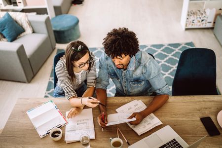 Couple sitting at desk with open computer and paperwork.