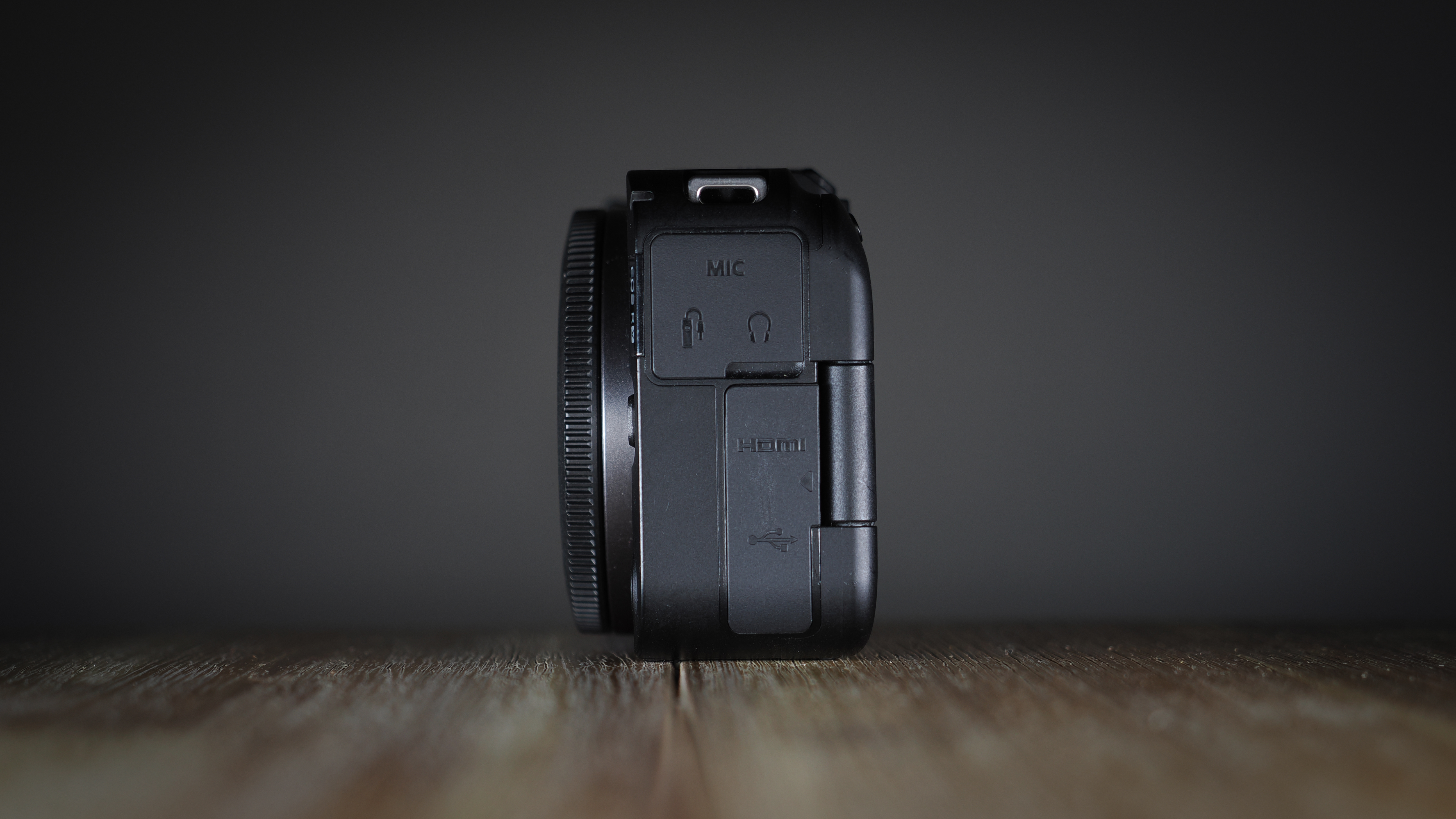 Canon EOS R50 V on a wooden surface, against a dark background