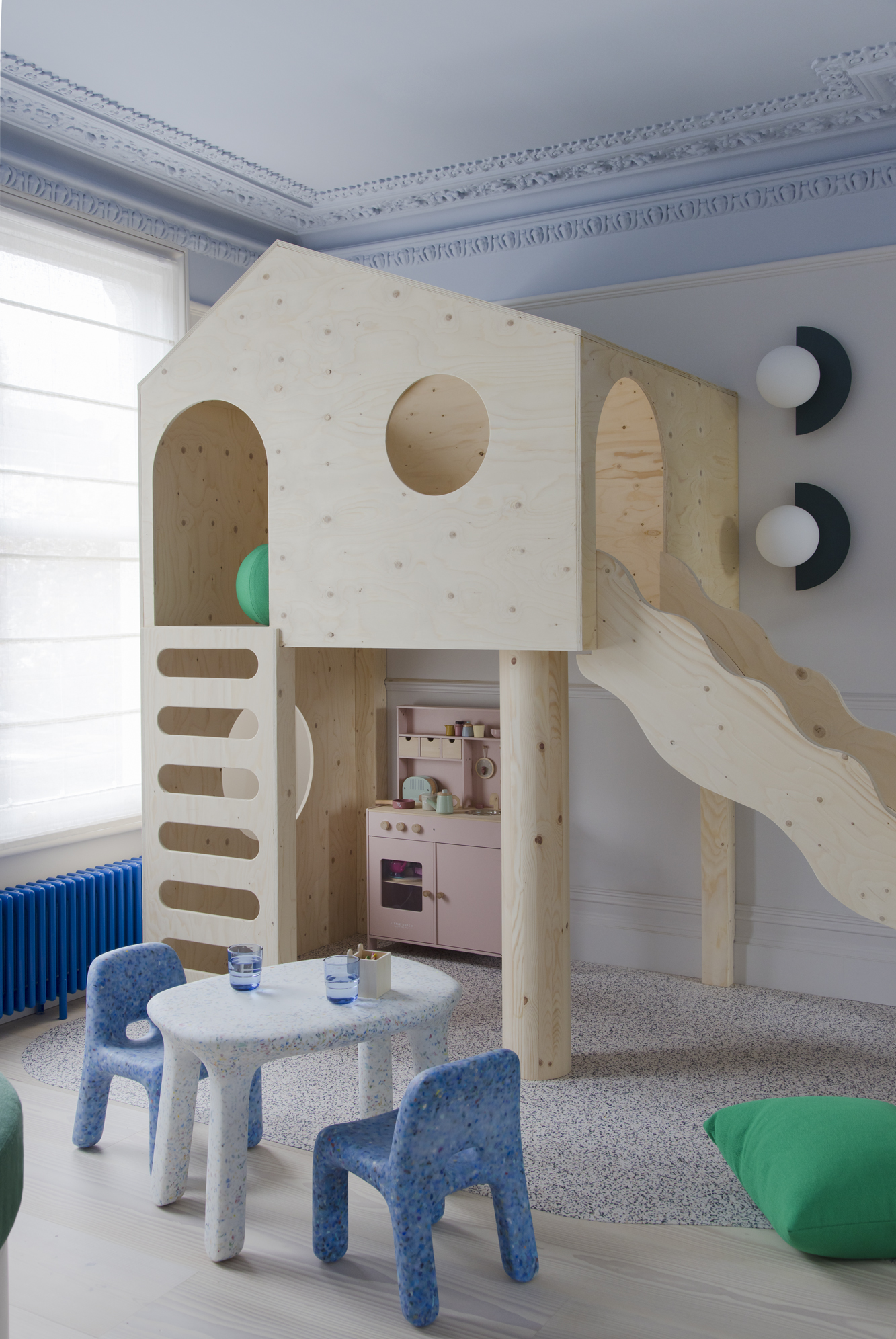 kids playroom with blue ceiling, kids furniture, plywood play house with slide, bright blue radiator, and pink play kitchen