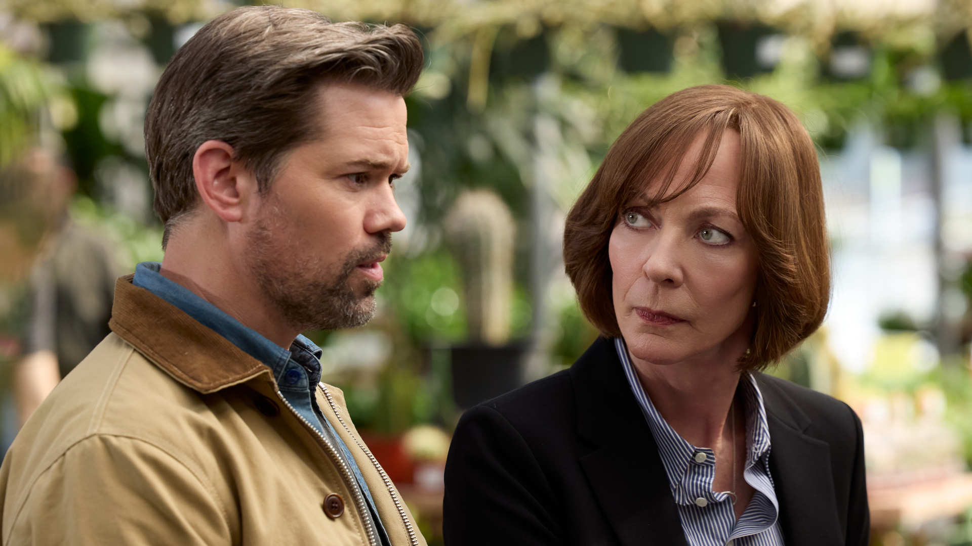 L-R: Andrew Rannells and Allison Janney sit together outdoors in a scene from "Miss You, Love You" on HBO Max