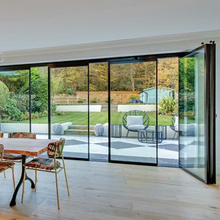 black aluminium slide and turn patio doors leading from dining room to modern patio