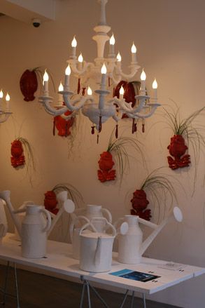 White ceramic watering cans on a table beneath a white chandelier