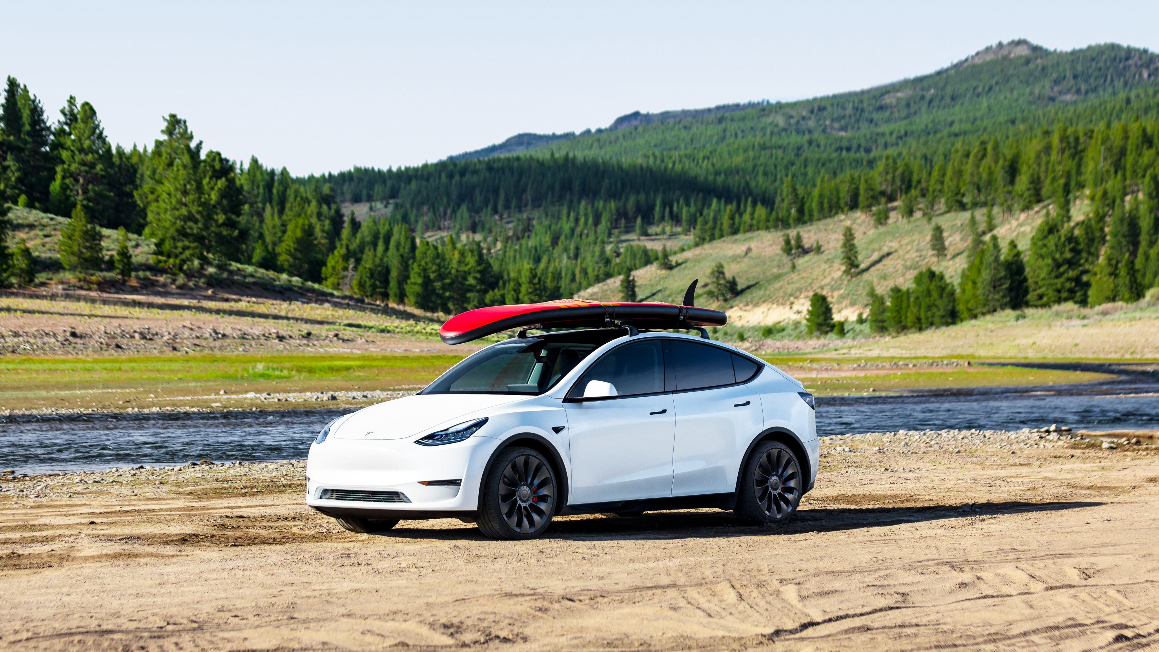 tesla model y with a surfboard on the roof