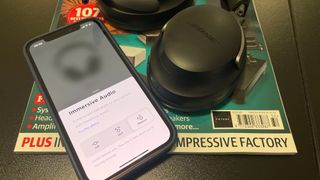 Bose Immersive Audio software on an iPhone next to Bose QC Ultra Headphones