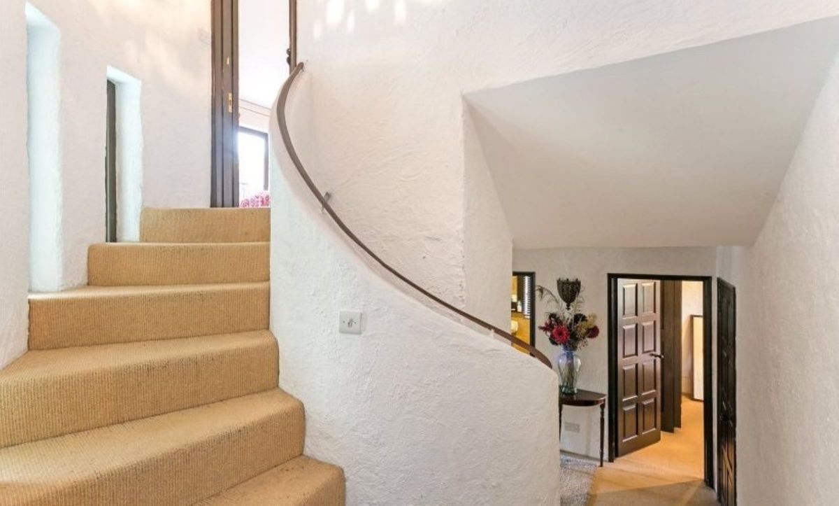 A curved staircase with orange carpet and white walls