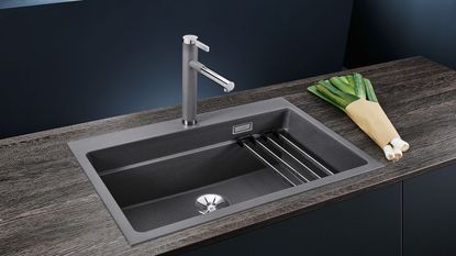 A black work station sink with a silver tap and a draining attachment 