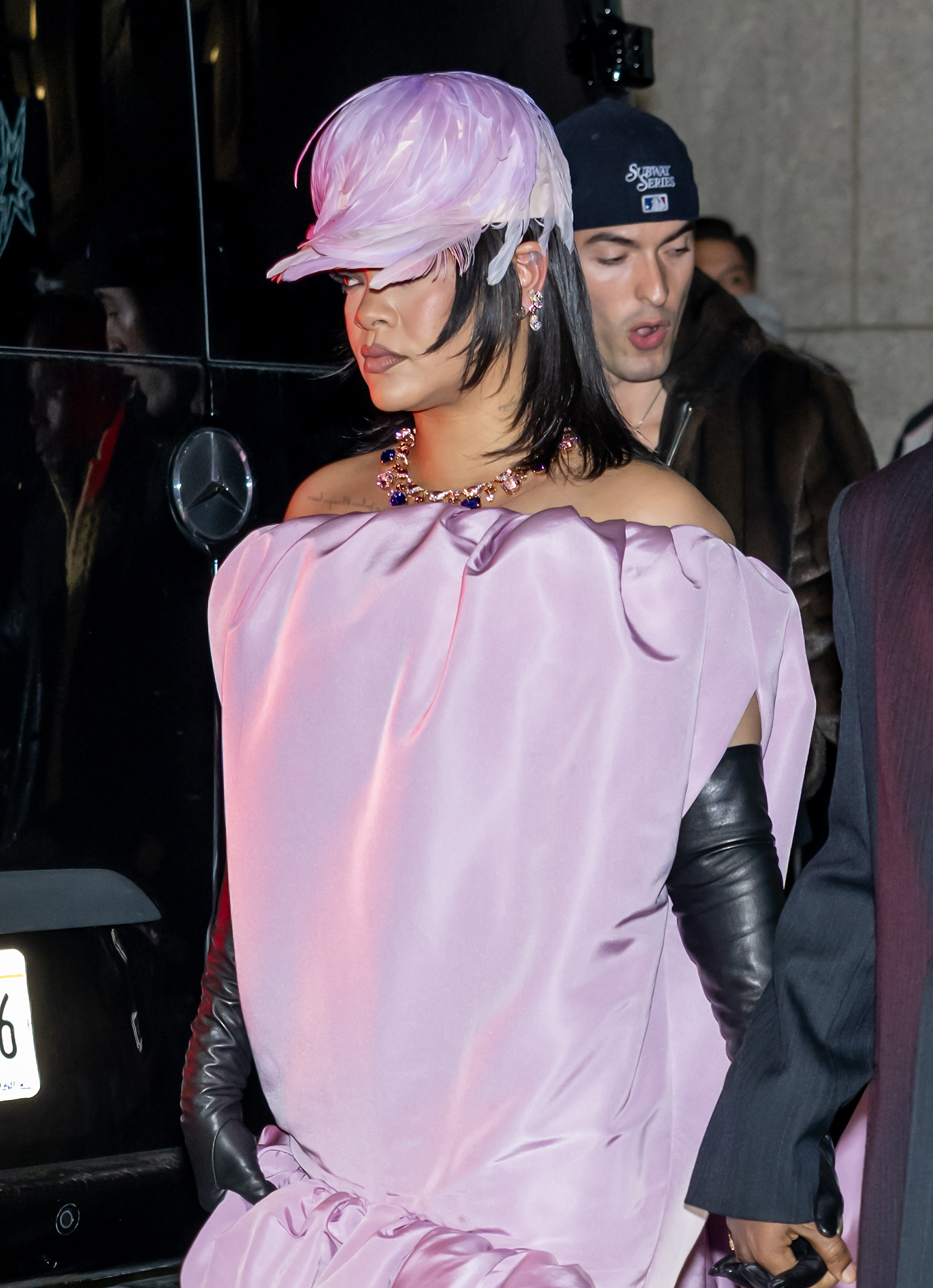 Rihanna wearing a purple balenciaga gown and a layered lob haircut. She is also wearing a feathered hat.