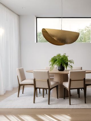 dining table with white linen curtains and gold pendant light
