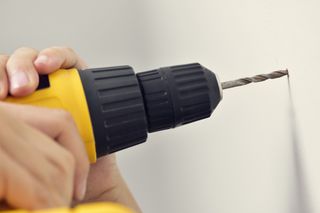 A person drilling a hole into a wall using a drill