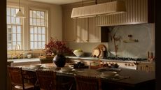 A warm neutral kitchen with slatted cabinets, a table-style island, and blue stone countertops and backsplash