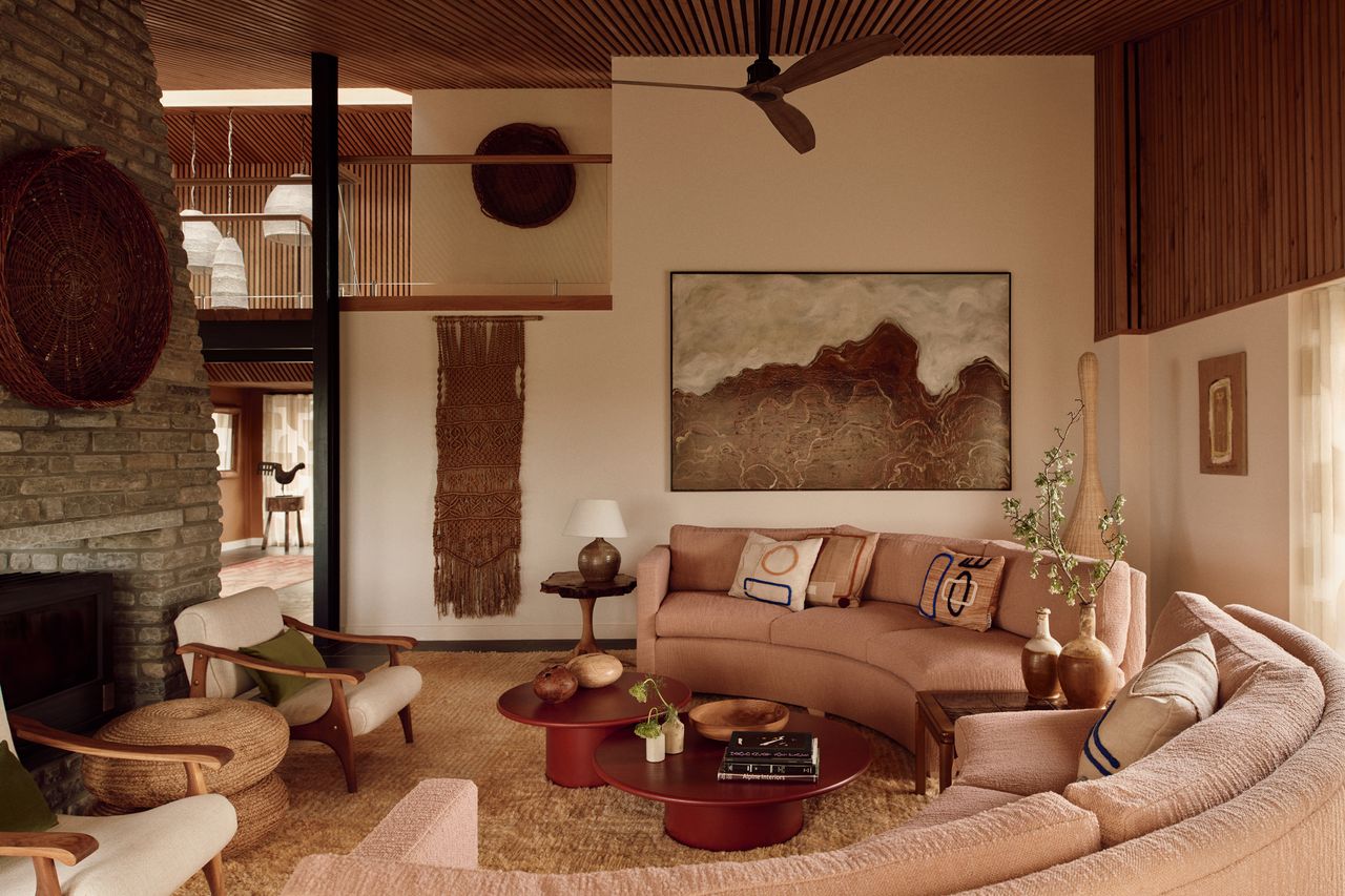 70s style living room with curved sofa around a nesting coffee table, shag rug, and brick fireplace with two armchairs in front of it