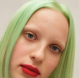 light green hair colour green juice by Bleach London with red lips and bleached eyebrows