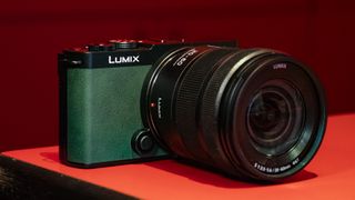 Panasonic Lumix S9 camera in Dark Olive color on a rich red reflective surface