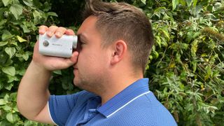 A man holds the Mileseey PF1 Golf Rangefinder up to his eye