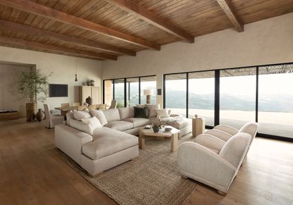 A neutral living room with large cream sofas and floor to ceiling windows