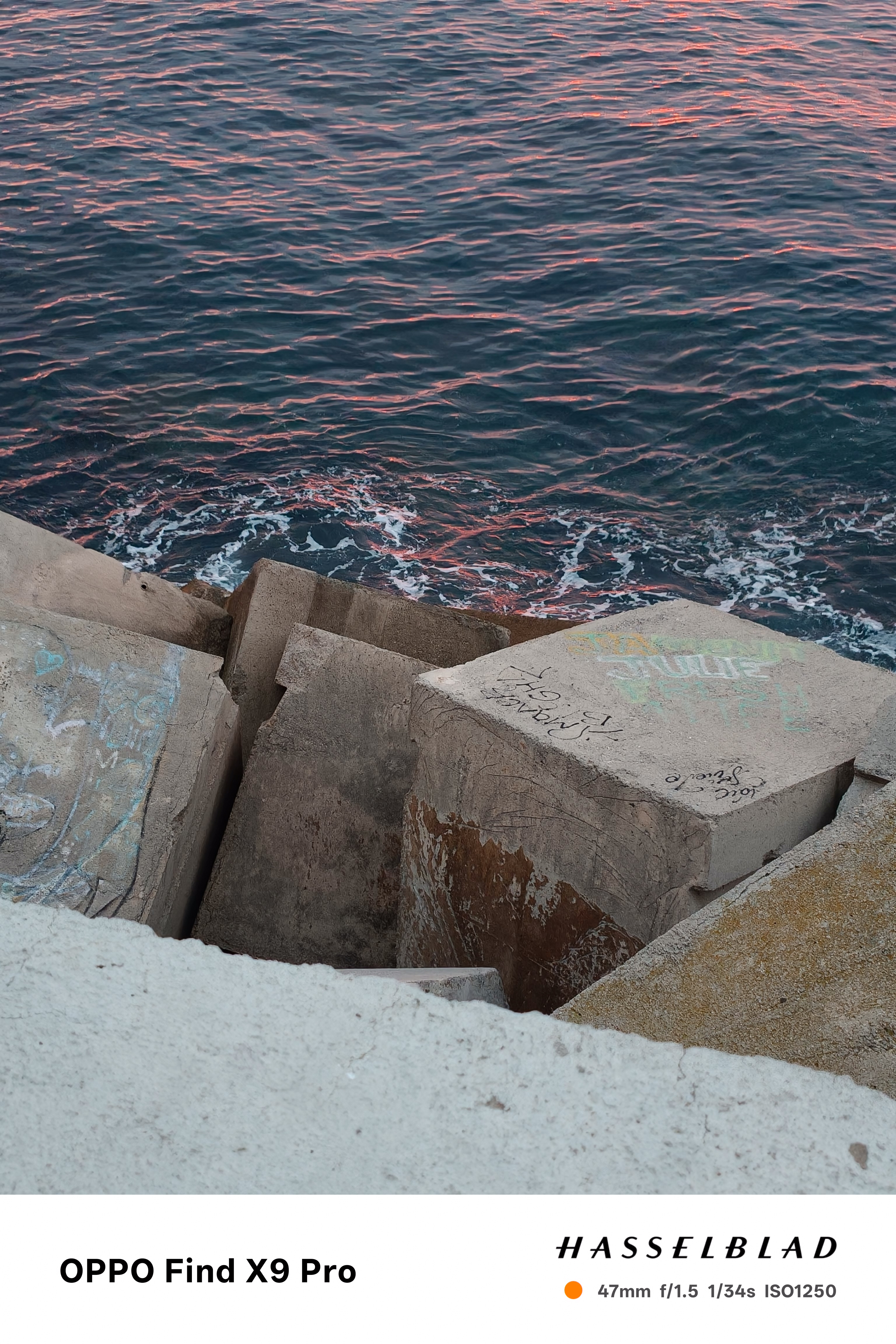 Concrete wave breakers next to the sea lit up red in the sunrise