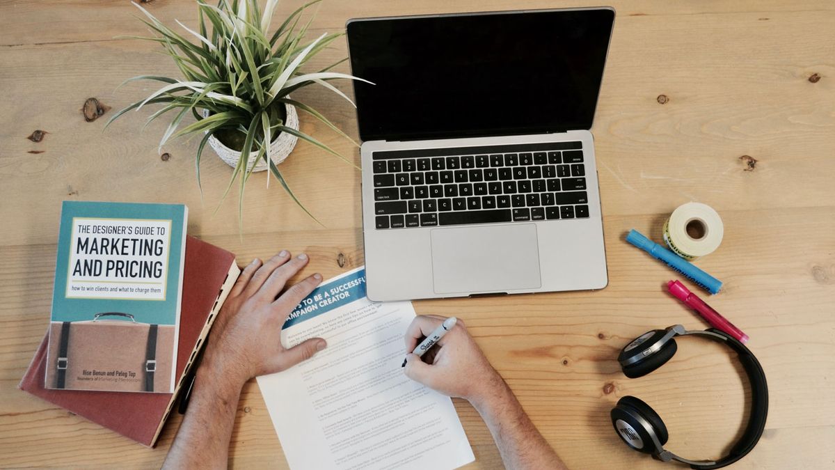 person writing notes at a desk on marketing strategy