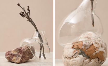 A glass vase that's blown around the rock. There are tree branches in the vase.