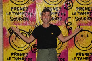 Artist André Saraiva, who has reimagined the Smiley logo for its 50th anniversary, in front of posters in Paris in February 2022