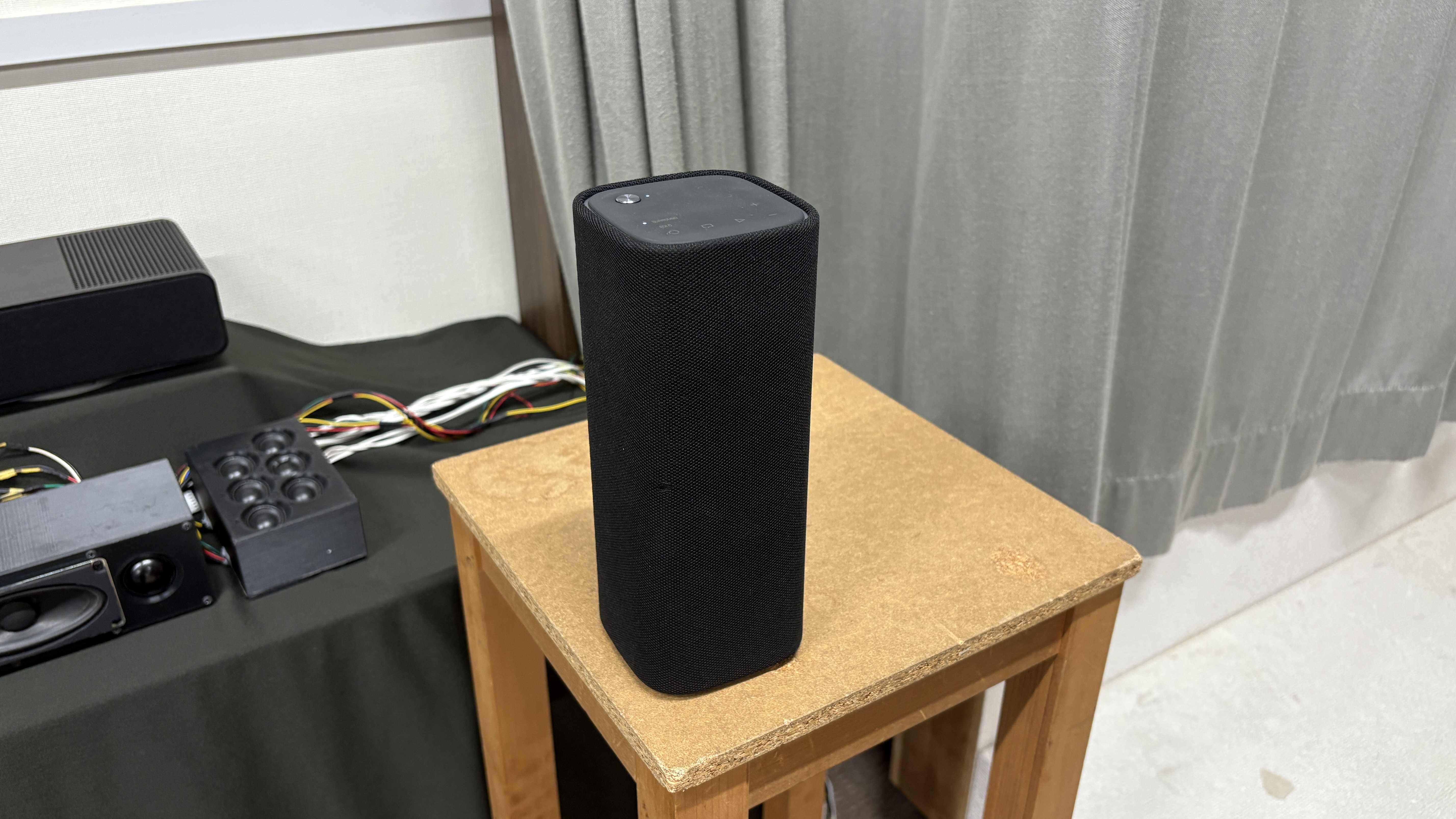 Yamaha True X Surround 90A system (soundbar, surround speakers and subwoofer) in a plain testing room with a TV.