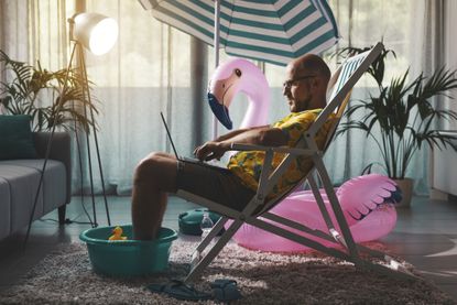 Man sitting in deck chair inside at home with inflatable flamingo