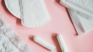 Tampons and pads on pink background - stock photo