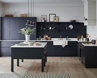 Monochrome kitchen scheme with charcoal island and cabinets and marble contrast work surfaces, and burnished brass hardware