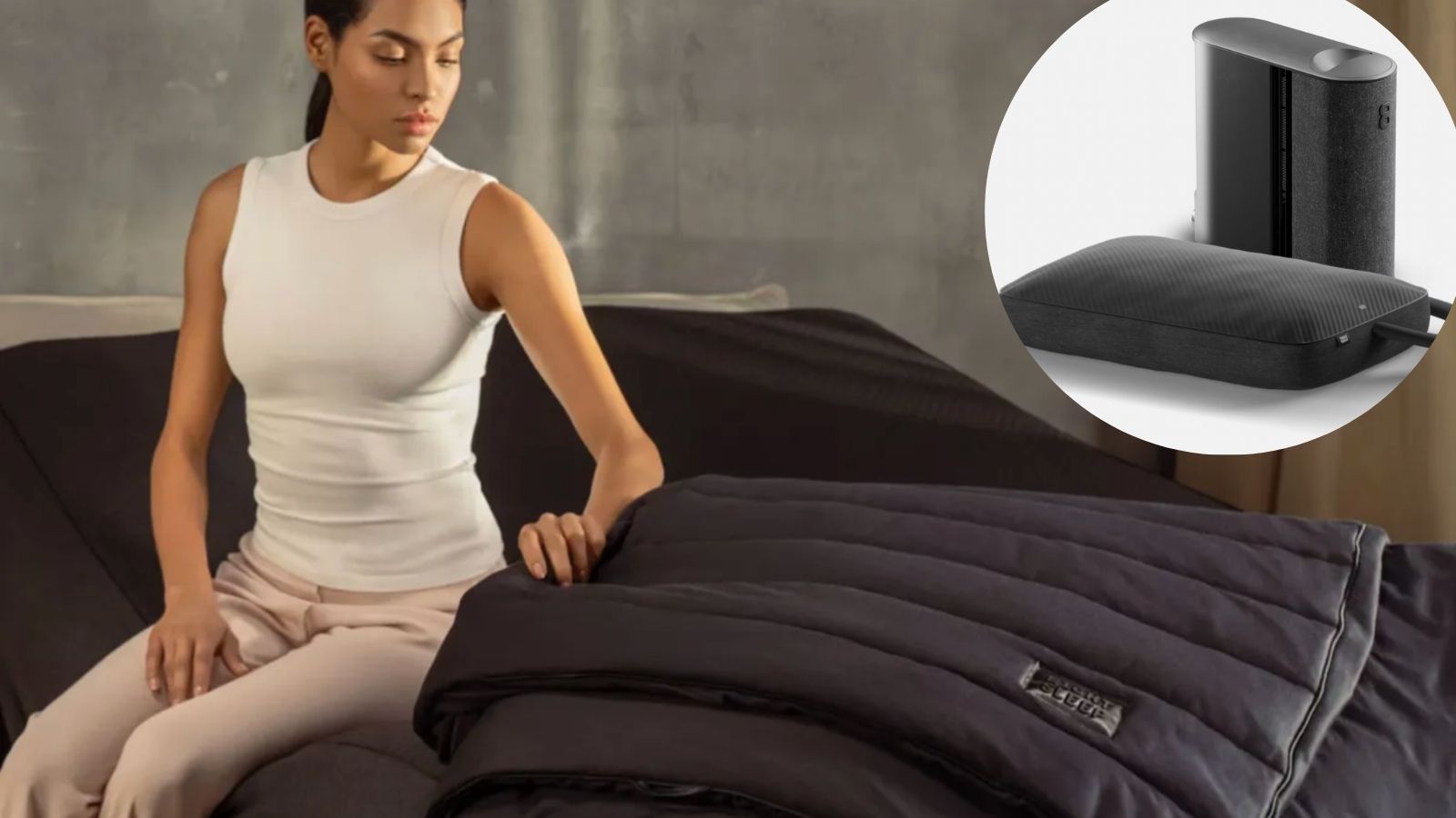 A woman wearing white vest top sat up on Eight Sleep Pod 5 on bed holding Eight Sleep thermo blanket with circular inset on black Eight Sleep smart pillow cover.