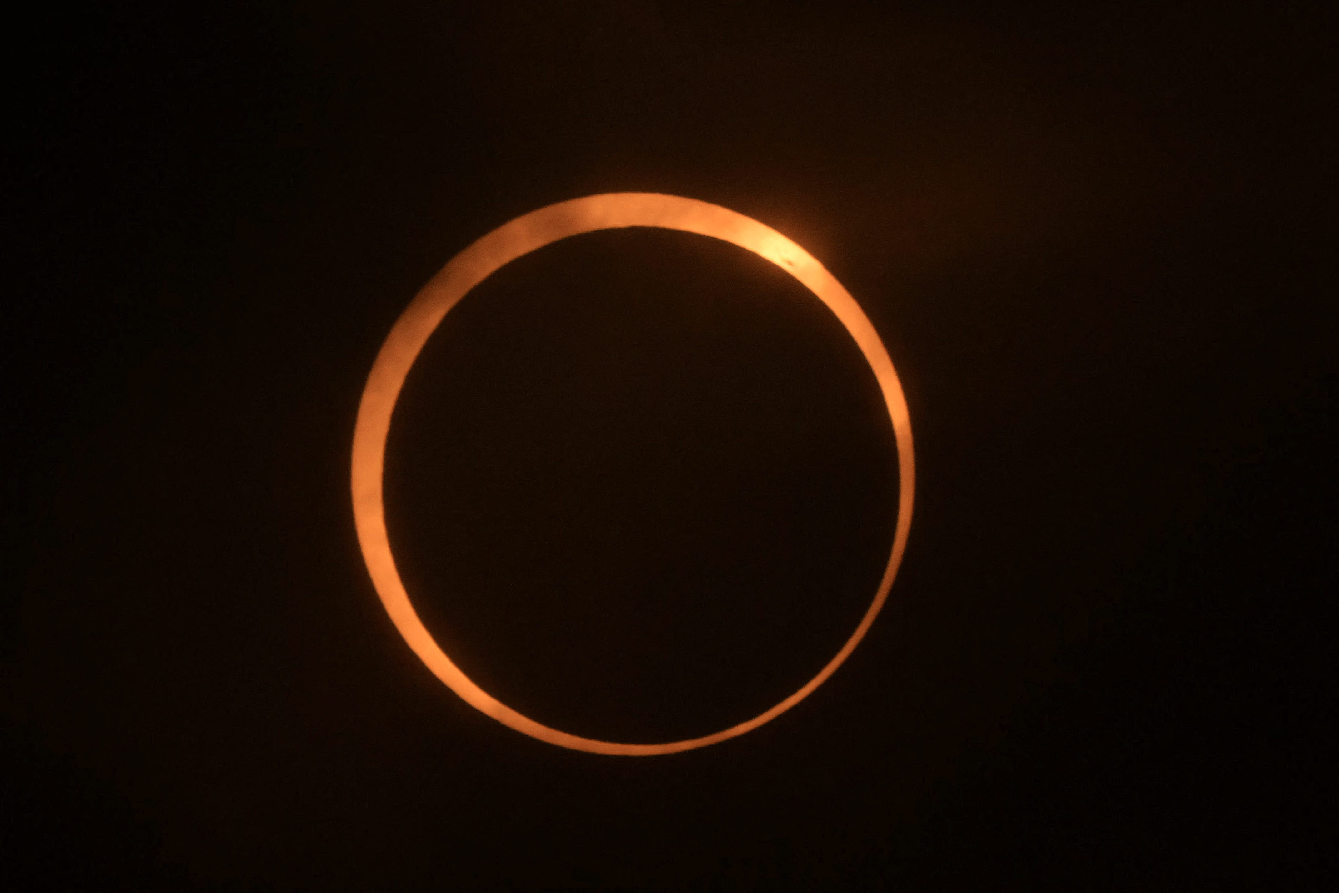 an orange ring of light with a dark circle in the middle and a black background behind.