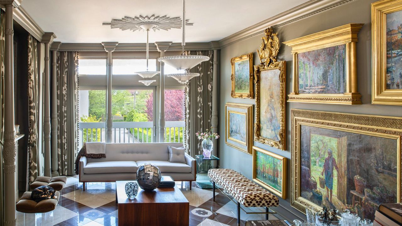 Living room with taupe walls gallery wall of paintings in gilt frames and marble floor