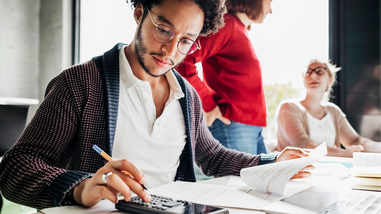 A young investor uses a calculator to do the math on average rate of return vs. actual rate of return.