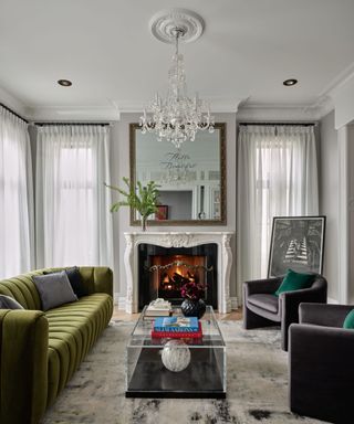 A living room with a green couch, a fireplace, and a glass coffee table