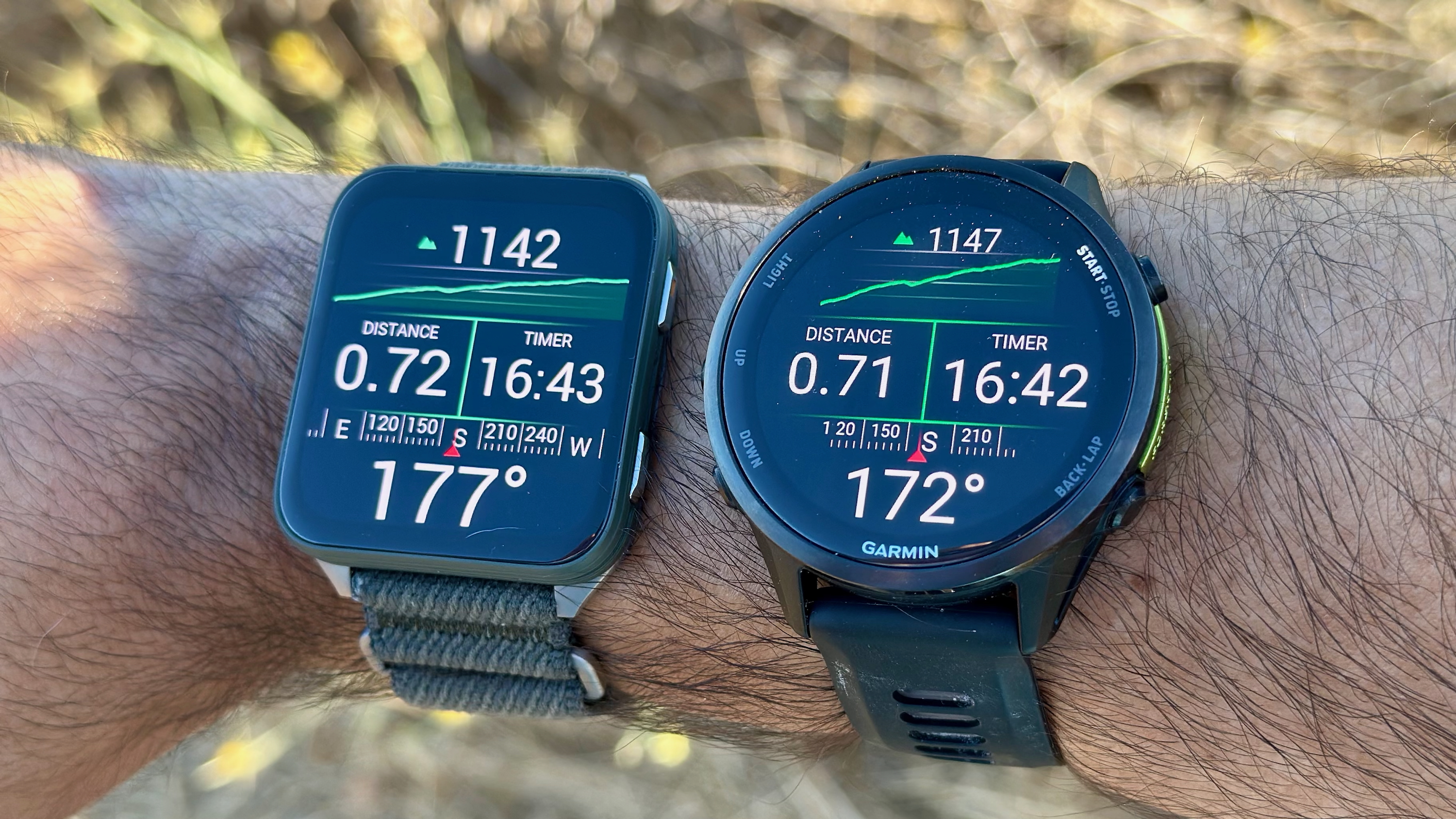 The Garmin Venu X1 (left) and Garmin Forerunner 970 (right), both on one wrist, showing near-identical stats for a hike activity&#039;s distance, time, elevation gain, and compass direction.