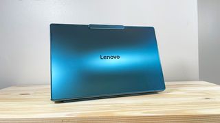 The glossy blue lid of the Lenovo Yoga Slim 9i on display on a wood table