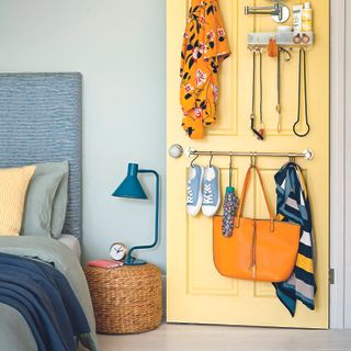 Bedroom with painted yellow door with hooks