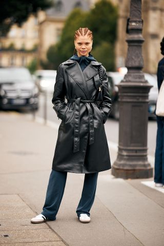 woman wearing leather trench coat, jeans, and adidas sambas