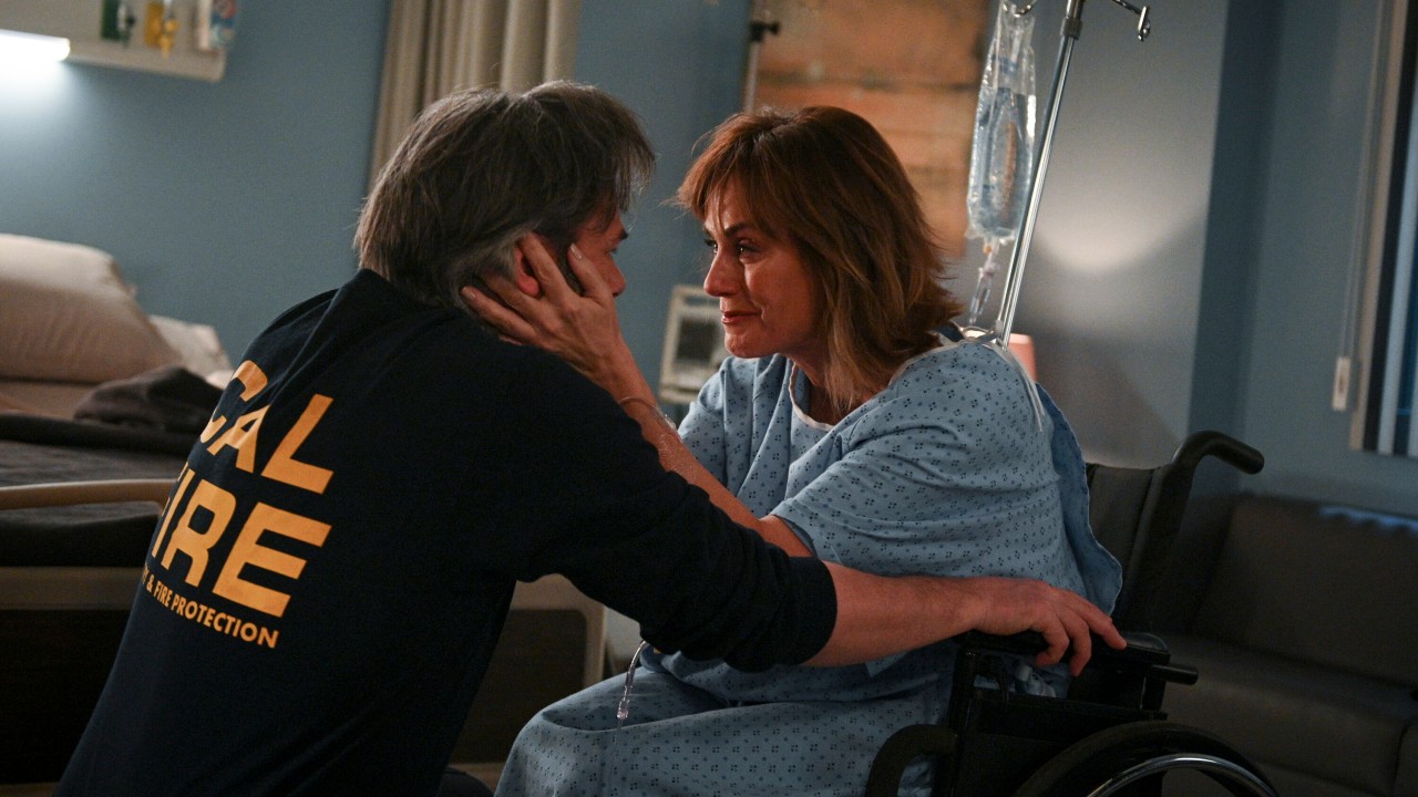 Billy Burke as Vince Leone and Diane Farr as Sharon Leone hold each other's faces in the hospital.