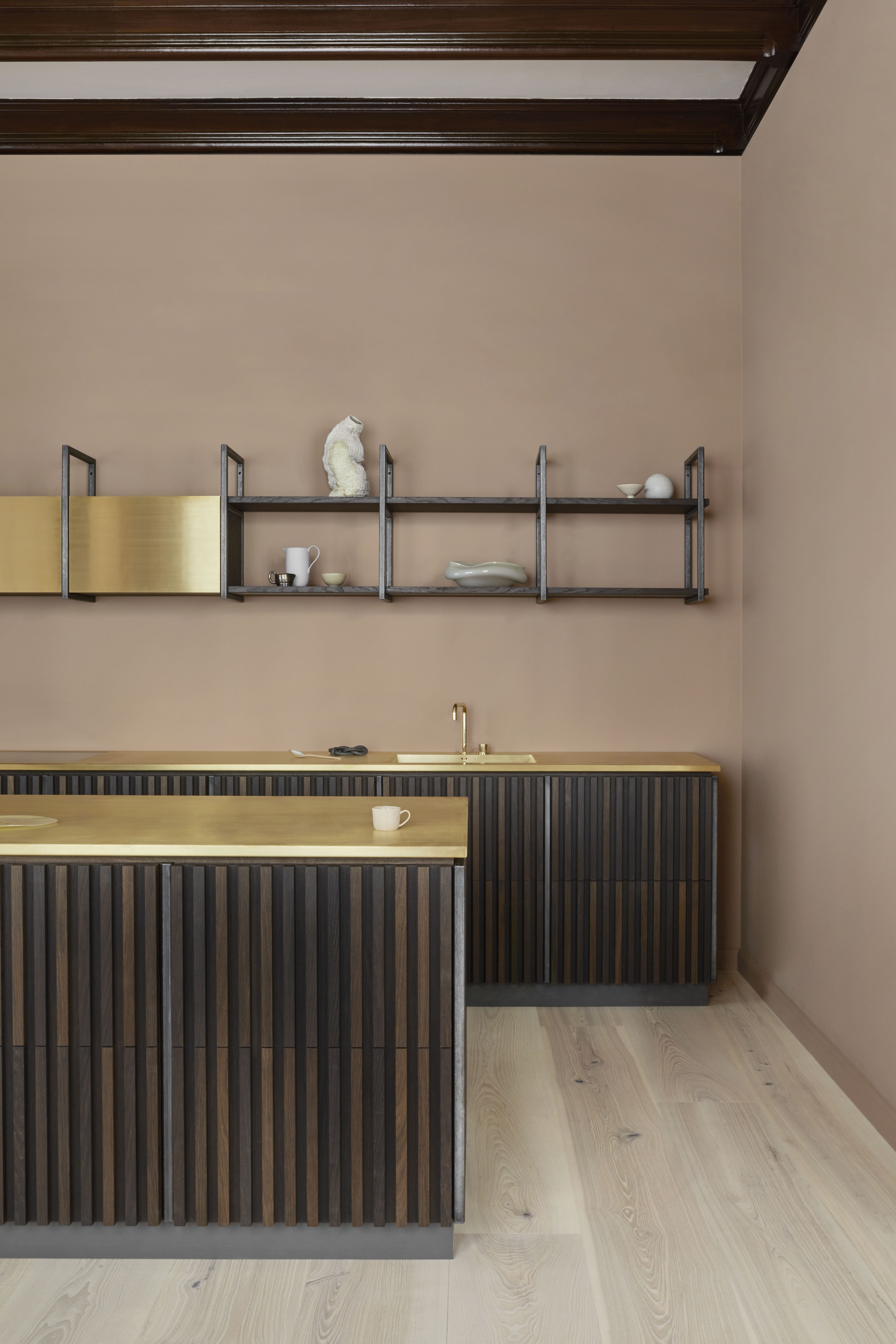 A kitchen with raw brass countertop, and wood island