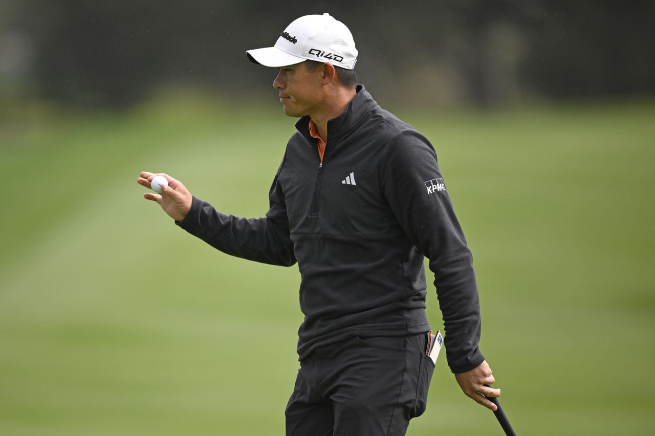 Collin Morikawa waves to fans after holing a putt