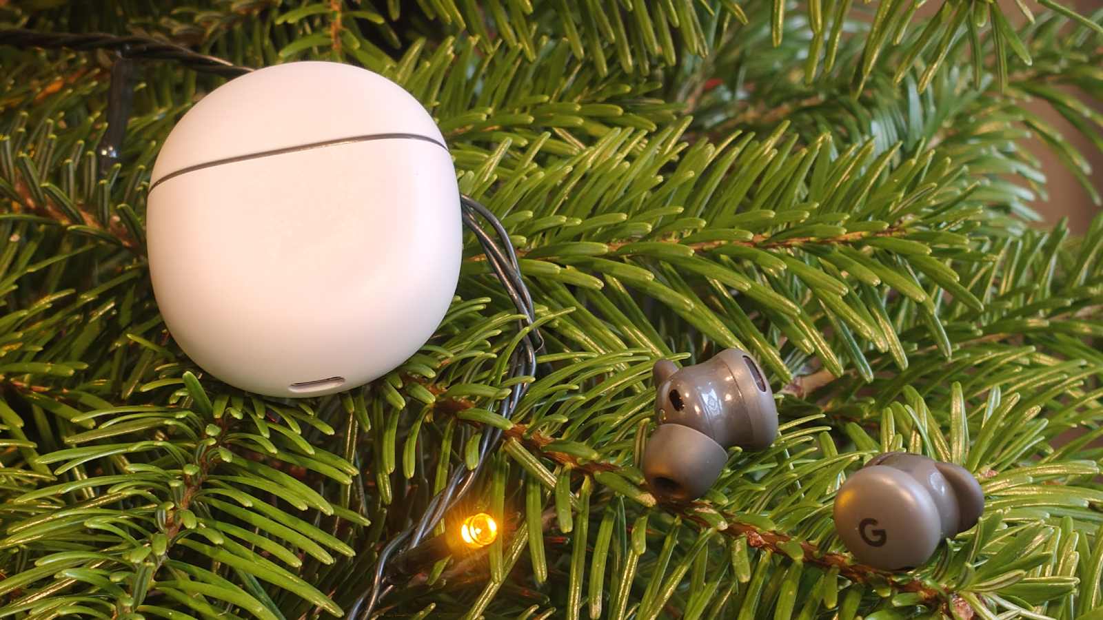 The Google Pixel Buds 2a earbuds on a tree, with the case to the side.