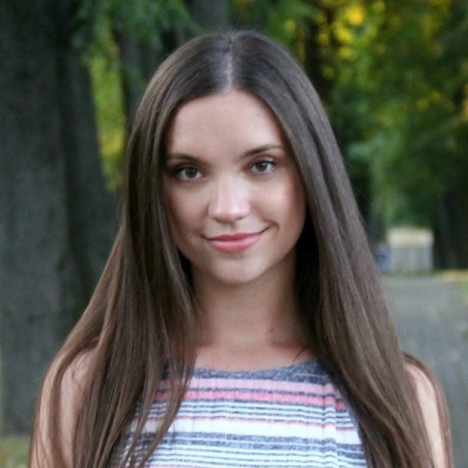 A headshot of a girl with long brown hair in a striped top