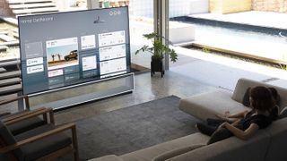 En LG Z Series 8K TV står på en TV-bänk i ett vardagsrum och visar ett gäng widgets på skärmen.