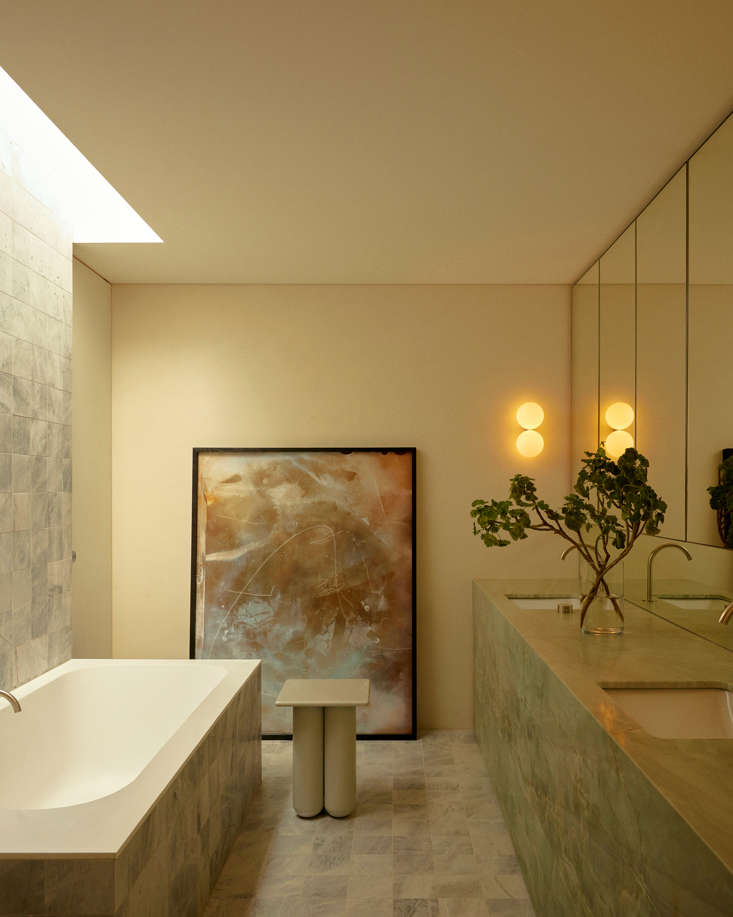 Bathroom with soft yellow walls and pale green stone vanity and bathtub