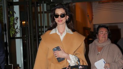 Anne Hathaway in a camel wool wrap coat and knee-high boots