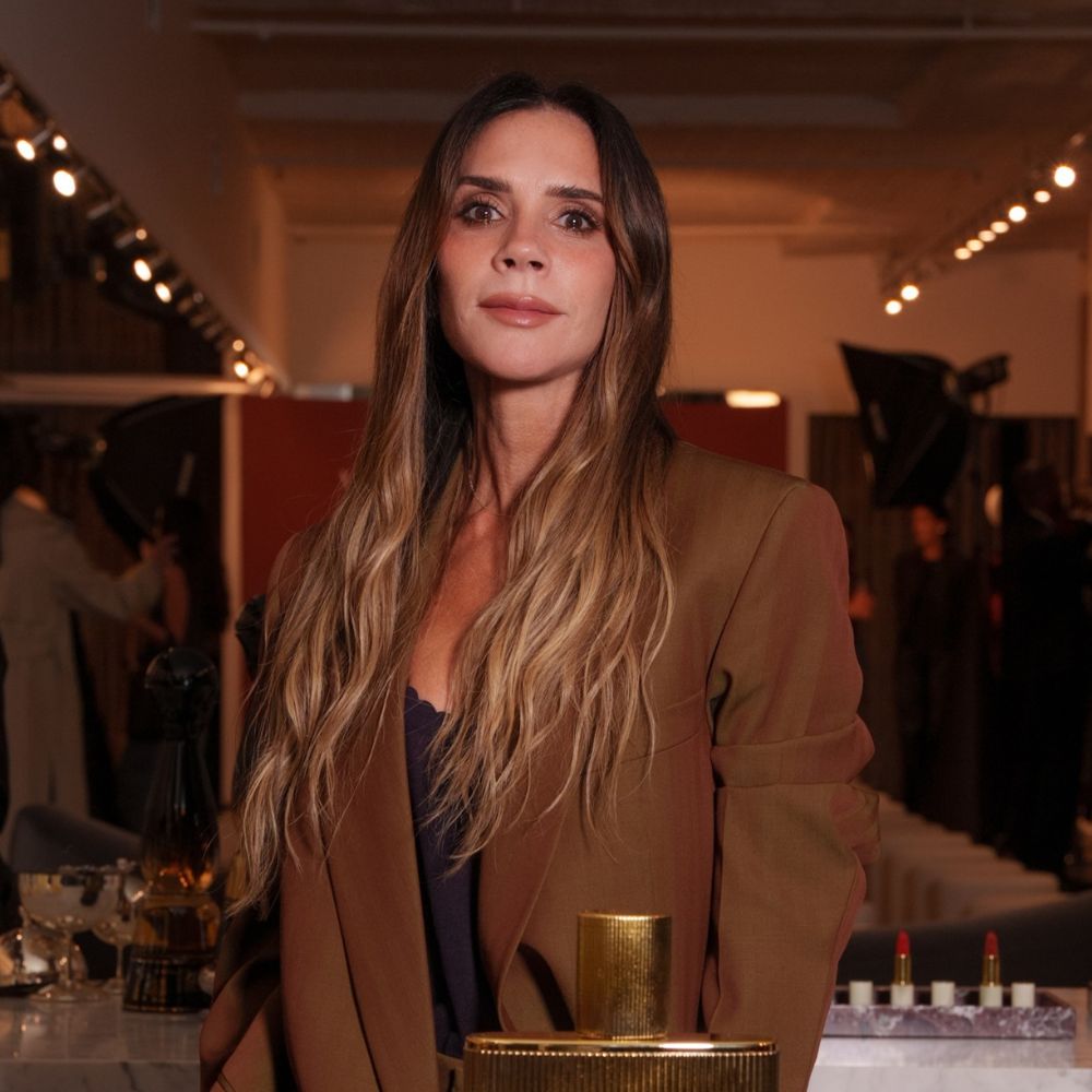 Victoria Beckham poses for a photo with Marc Jacobs wearing a brown oversized suit with a black camisole top.