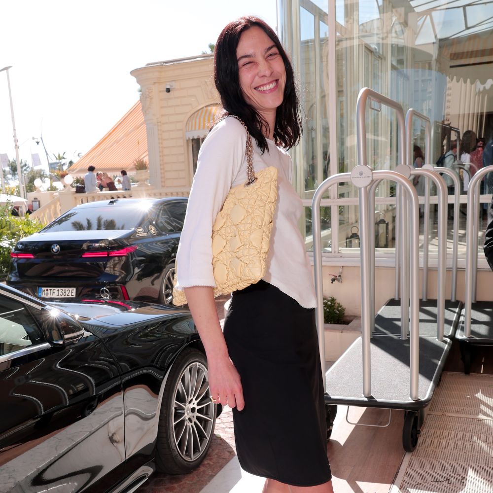 Alexa Chung wears leopard print heeled flip flops with a black pencil skirt, a white t-shirt and a yellow bag.