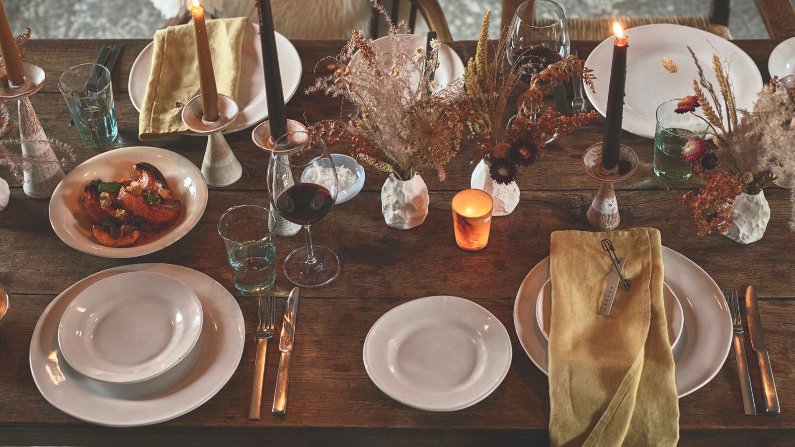 Aerial view of wooden dining table with yellow linen napkins and black taper candles