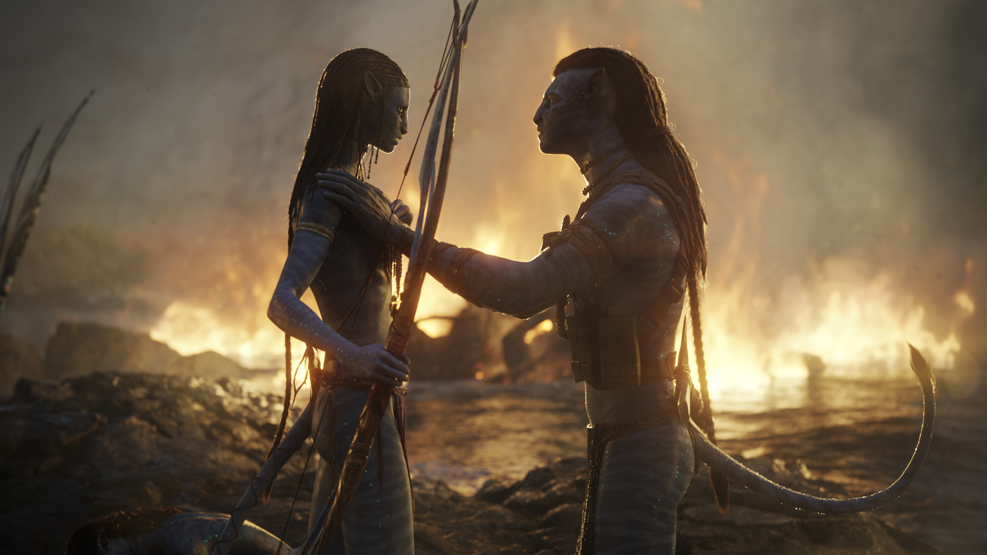 Jake kneels down as he speaks to Kiri against a fiery backdrop in Avatar: The Way of Water