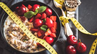 Bowl of porridge with berries and tape measure laying on top