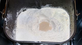 Flour and yeast added to a bread maker pan